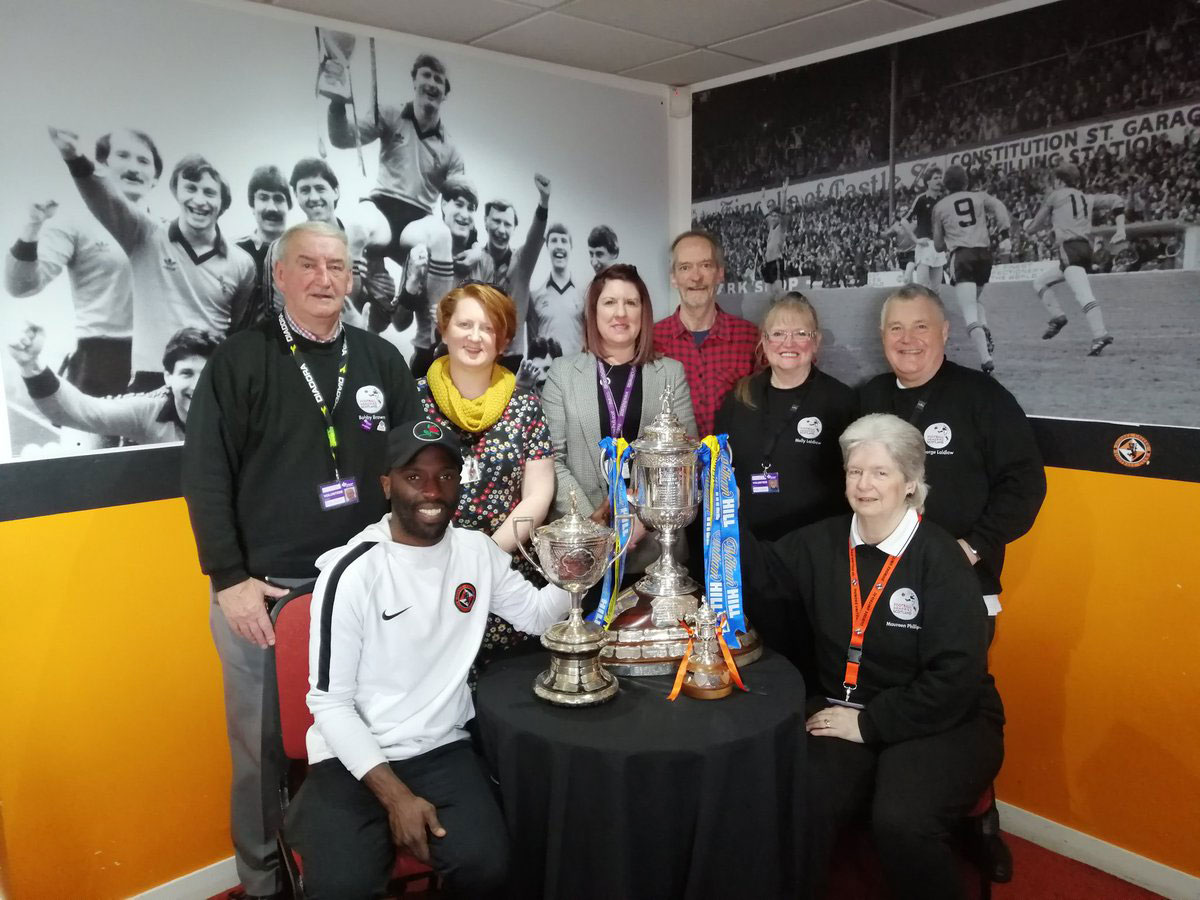 Staff and volunteers of the Dundee United Football Memories group pictured with Morgamo Gomis, the Scottish Cup and Second XI Cup